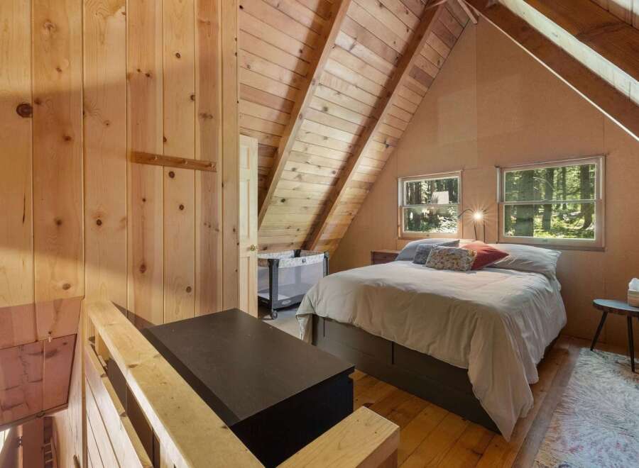 Experience rustic charm in this cozy cabin bedroom, featuring warm wood paneling and a vaulted ceiling with exposed beams.