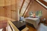 Experience rustic charm in this cozy cabin bedroom, featuring warm wood paneling and a vaulted ceiling with exposed beams.