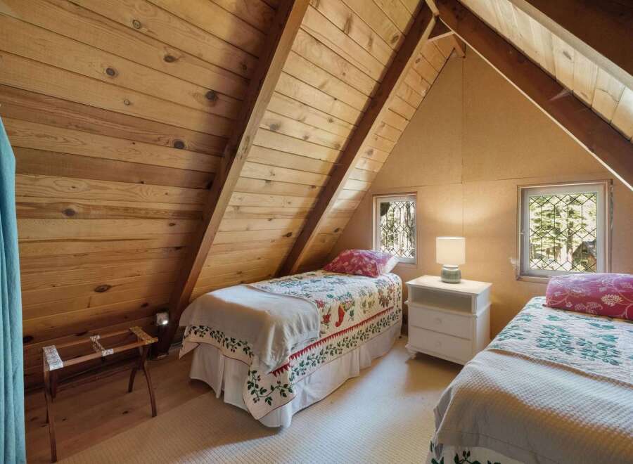 Discover this charming attic bedroom, featuring two cozy twin beds adorned with floral quilts.