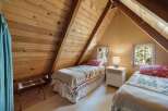Discover this charming attic bedroom, featuring two cozy twin beds adorned with floral quilts.