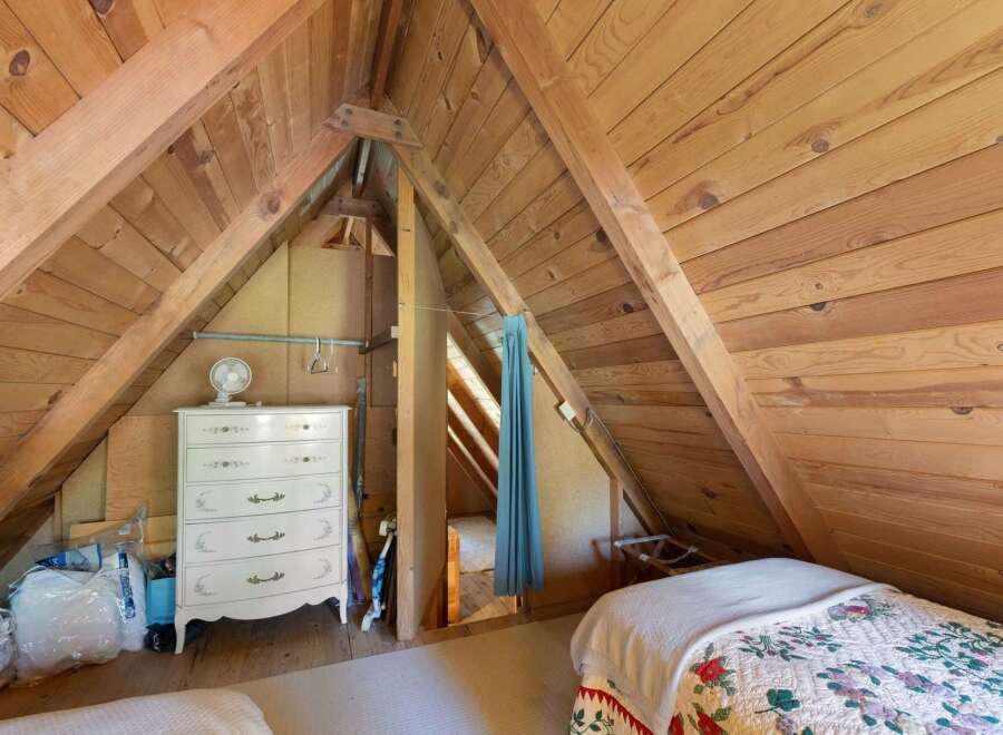 Discover unique living spaces with this charming attic bedroom, featuring exposed wooden beams and a cozy, rustic ambiance.