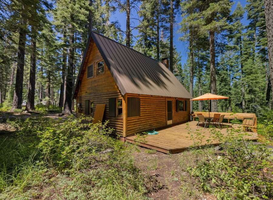 Escape to this charming A-frame cabin nestled amongst tall pine trees, offering a serene forest retreat.