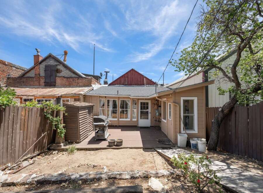 Enjoy outdoor living in this charming backyard featuring a spacious deck perfect for entertaining, complete with a grill and a convenient storage shed.