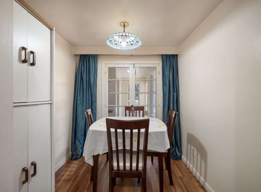 This dining area features a charming stained-glass pendant light illuminating a wooden table set with a white tablecloth.