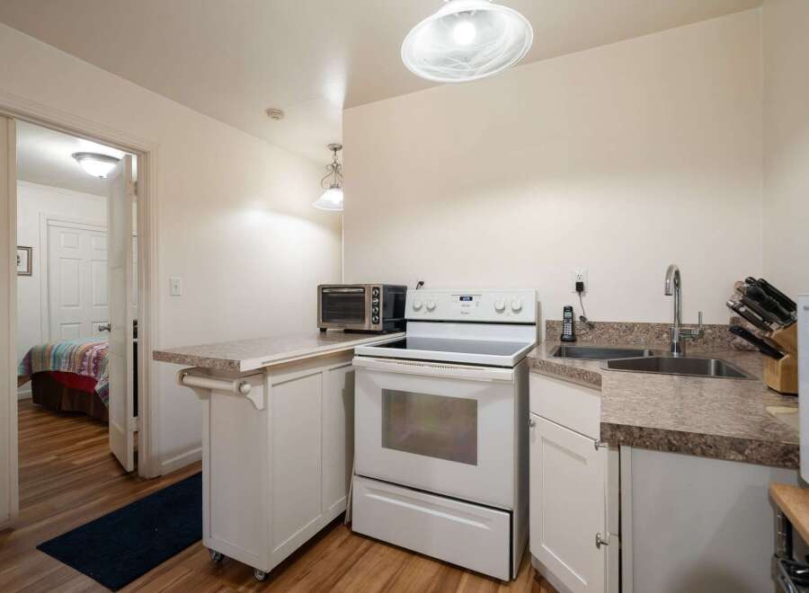 This charming kitchen features a full-sized electric range and a compact toaster oven, perfect for preparing meals.