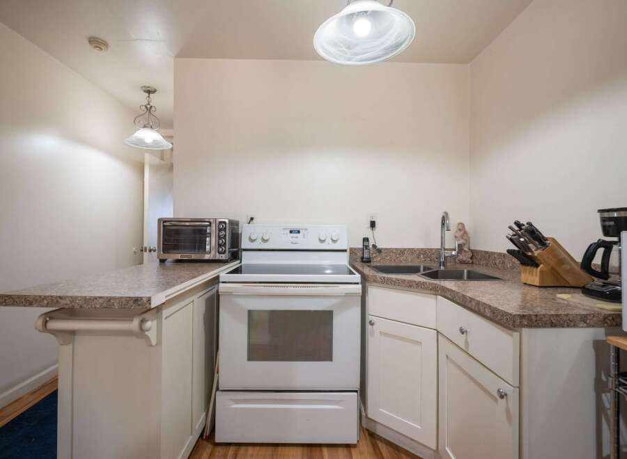 Discover this charming kitchen featuring a sleek white electric range and a convenient countertop toaster oven.