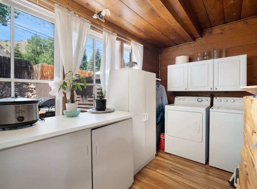 This charming laundry room features a spacious countertop with a Crock-Pot and a plant, perfect for multitasking.