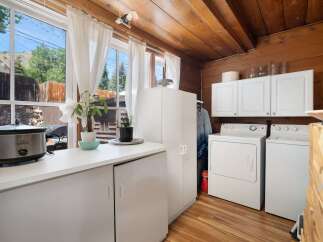 This charming laundry room features a spacious countertop with a Crock-Pot and a plant, perfect for multitasking.