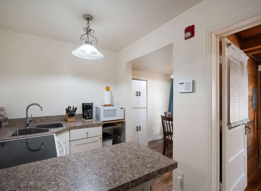 Discover this charming kitchen featuring a double sink, coffee maker, and microwave, perfect for everyday meals.