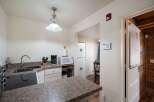 Discover this charming kitchen featuring a double sink, coffee maker, and microwave, perfect for everyday meals.