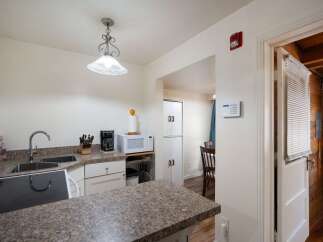 Discover this charming kitchen featuring a double sink, coffee maker, and microwave, perfect for everyday meals.