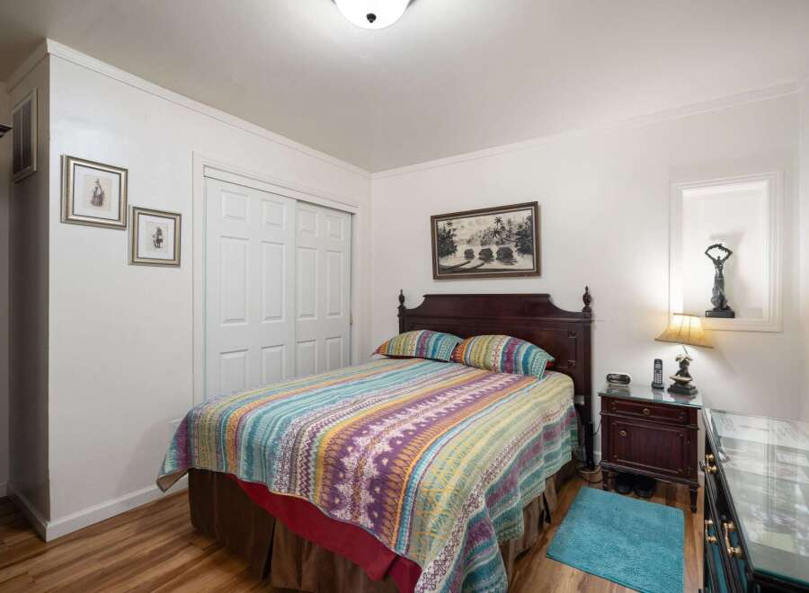 This charming bedroom features a cozy queen-size bed adorned with a vibrant, patterned quilt and matching pillows.