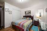 This charming bedroom features a cozy queen-size bed adorned with a vibrant, patterned quilt and matching pillows.