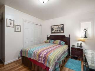 This charming bedroom features a cozy queen-size bed adorned with a vibrant, patterned quilt and matching pillows.