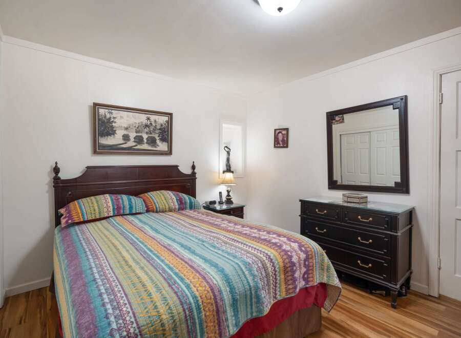 This charming bedroom features a comfortable queen-size bed with a vibrant, patterned quilt and matching pillows.