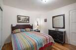 This charming bedroom features a comfortable queen-size bed with a vibrant, patterned quilt and matching pillows.
