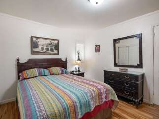 This charming bedroom features a comfortable queen-size bed with a vibrant, patterned quilt and matching pillows.