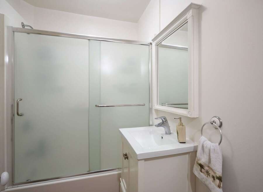 This bathroom features a sleek glass-enclosed shower and a modern vanity with a clean white countertop.