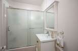 This bathroom features a sleek glass-enclosed shower and a modern vanity with a clean white countertop.