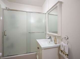 This bathroom features a sleek glass-enclosed shower and a modern vanity with a clean white countertop.
