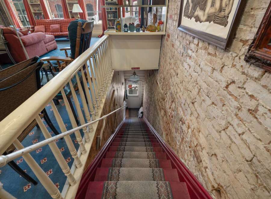 Descend into this charming space via a carpeted staircase with a classic red runner and ornate railing.