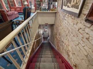 Descend into this charming space via a carpeted staircase with a classic red runner and ornate railing.