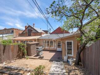 Enjoy outdoor living in this charming backyard featuring a spacious deck perfect for entertaining, complete with a grill and a convenient storage shed.