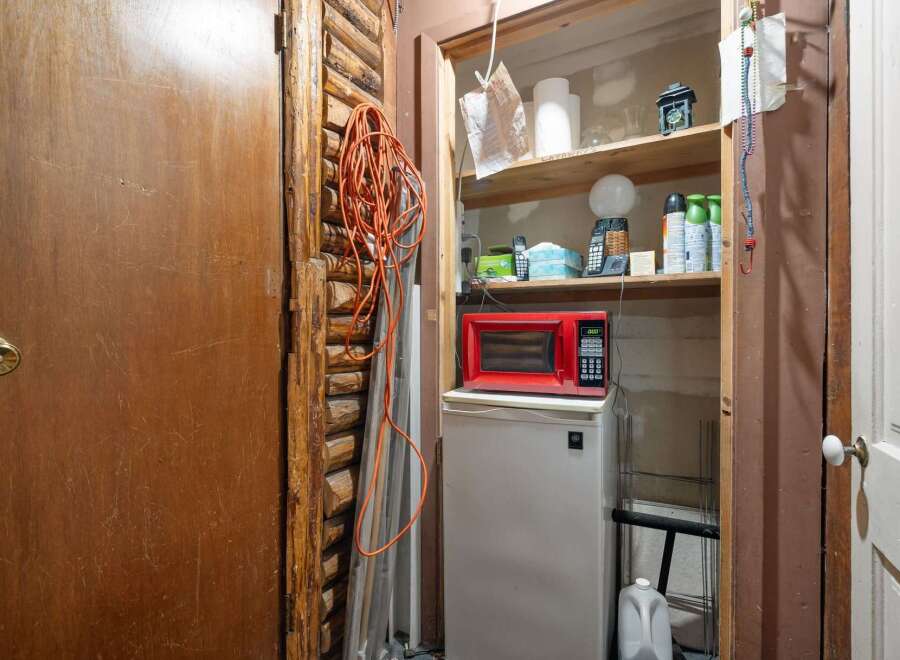 Discover practical storage solutions in this space, featuring a compact refrigerator topped with a red microwave, perfect for a small kitchen or utility area.