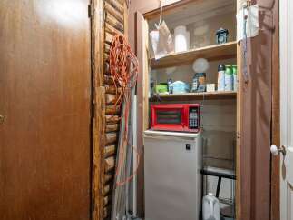 Discover practical storage solutions in this space, featuring a compact refrigerator topped with a red microwave, perfect for a small kitchen or utility area.