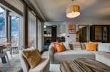 Experience breathtaking mountain views from this stunning living space, featuring a comfortable sectional sofa adorned with vibrant orange accents and a cozy throw blanket.