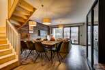 Experience modern mountain living in this stunning open-plan space, featuring a rustic wood-paneled accent wall and a cozy dining area perfect for gathering.