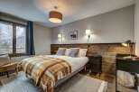 Experience cozy mountain living in this charming bedroom, featuring a comfortable bed adorned with a warm plaid throw and plush pillows.