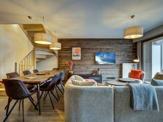 Experience modern mountain living in this stunning open-concept space, featuring a rustic wood-paneled accent wall and a cozy living area.