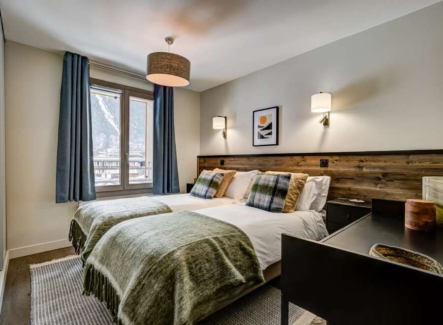 Experience comfort and style in this inviting bedroom featuring two twin beds adorned with plush plaid pillows and cozy green throws.