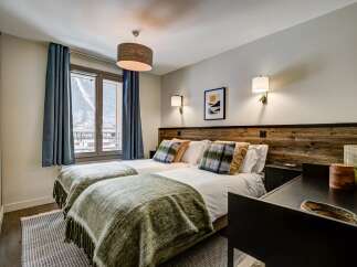 Experience comfort and style in this inviting bedroom featuring two twin beds adorned with plush plaid pillows and cozy green throws.