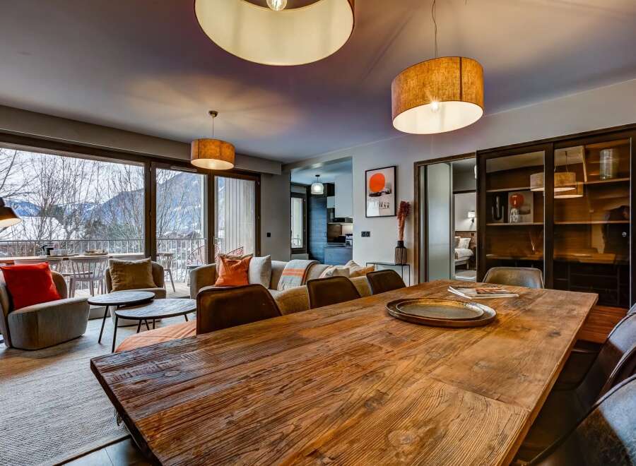 Experience luxurious mountain living in this stunning apartment, featuring a spacious dining area with a rustic wooden table perfect for gatherings.