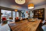 Experience luxurious mountain living in this stunning apartment, featuring a spacious dining area with a rustic wooden table perfect for gatherings.