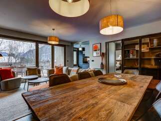 Experience luxurious mountain living in this stunning apartment, featuring a spacious dining area with a rustic wooden table perfect for gatherings.