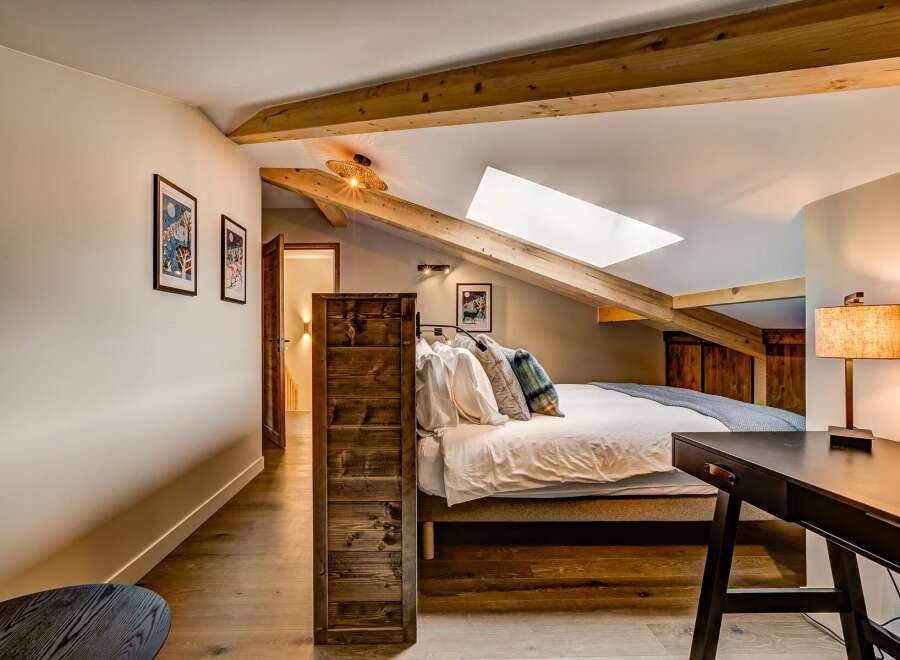 Experience cozy living in this charming attic bedroom, featuring exposed wooden beams and a skylight that floods the space with natural light.