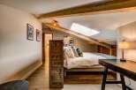 Experience cozy living in this charming attic bedroom, featuring exposed wooden beams and a skylight that floods the space with natural light.