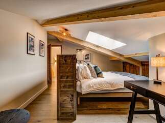 Experience cozy living in this charming attic bedroom, featuring exposed wooden beams and a skylight that floods the space with natural light.