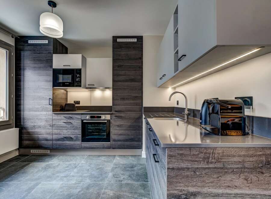 Experience modern living in this sleek kitchen featuring dark wood cabinetry and a minimalist aesthetic.