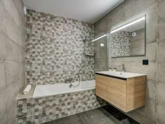 Experience modern comfort in this beautifully designed bathroom, featuring a sleek bathtub with a hexagonal tile accent wall.