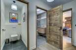 Step into a modern and inviting hallway featuring a stylish powder room with unique artwork and a sleek toilet.