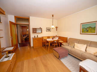 This cozy living and dining area features warm wooden floors and a comfortable L-shaped banquette seating arrangement perfect for family meals.