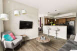 Experience modern living in this open-concept condo featuring a stylish living area with a wall-mounted TV and a comfortable armchair.