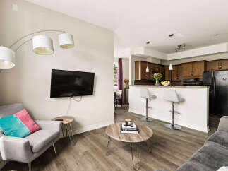 Experience modern living in this open-concept condo featuring a stylish living area with a wall-mounted TV and a comfortable armchair.
