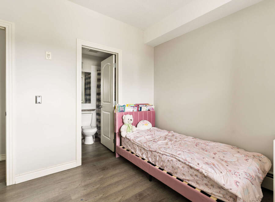 This charming bedroom features a cozy pink twin bed adorned with a whimsical unicorn-themed comforter and plush toys.