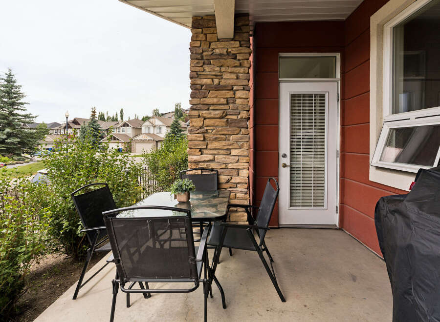 Enjoy outdoor living on this charming patio, complete with a glass-top dining table and four black mesh chairs, perfect for al fresco meals.