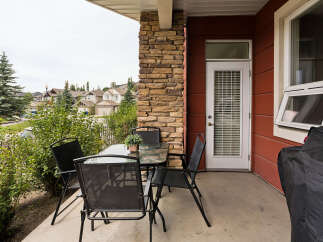 Enjoy outdoor living on this charming patio, complete with a glass-top dining table and four black mesh chairs, perfect for al fresco meals.